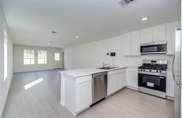 a kitchen with stainless steel appliances granite countertop a stove a sink and a microwave