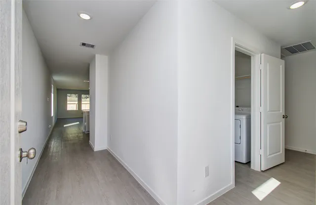 a view of a hallway with wooden floor and closet