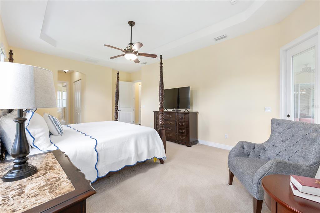 5024 Southwest 114th Street Road Ocala, FL 34476 - Photo 29 of 56 a spacious bedroom with a bed chandelier and a window
