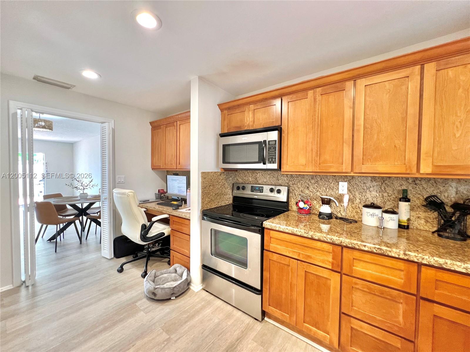 8114 Southwest 81st Terrace Miami, FL 33143 - Photo 8 of 20 a kitchen with stainless steel appliances granite countertop a stove top oven a sink dishwasher and cabinets with wooden floor