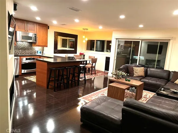 a living room with stainless steel appliances furniture and a kitchen view