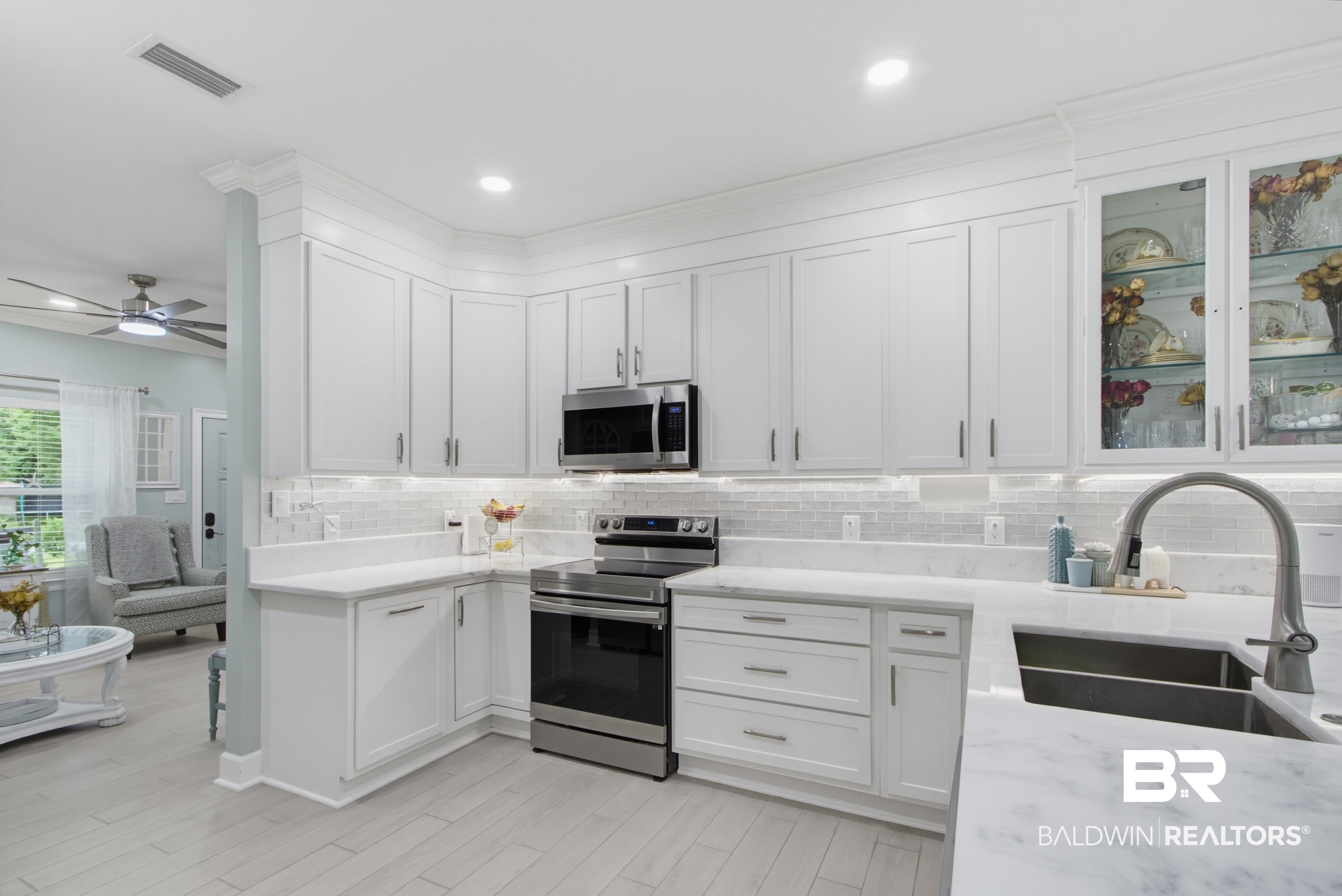 7472 Coopers Landing Road Foley, AL 36535 - Photo 7 of 40 Contemporary kitchen featuring white cabinetry, a subway tile backsplash, stainless steel appliances, and tile wood-finish flooring
