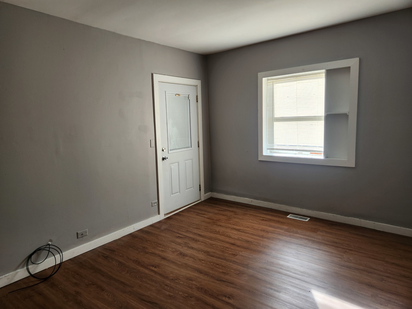 106 West Comanche Avenue, Unit 1E Shabbona, IL 60550 - Photo 3 of 9 an empty room with wooden floor and windows