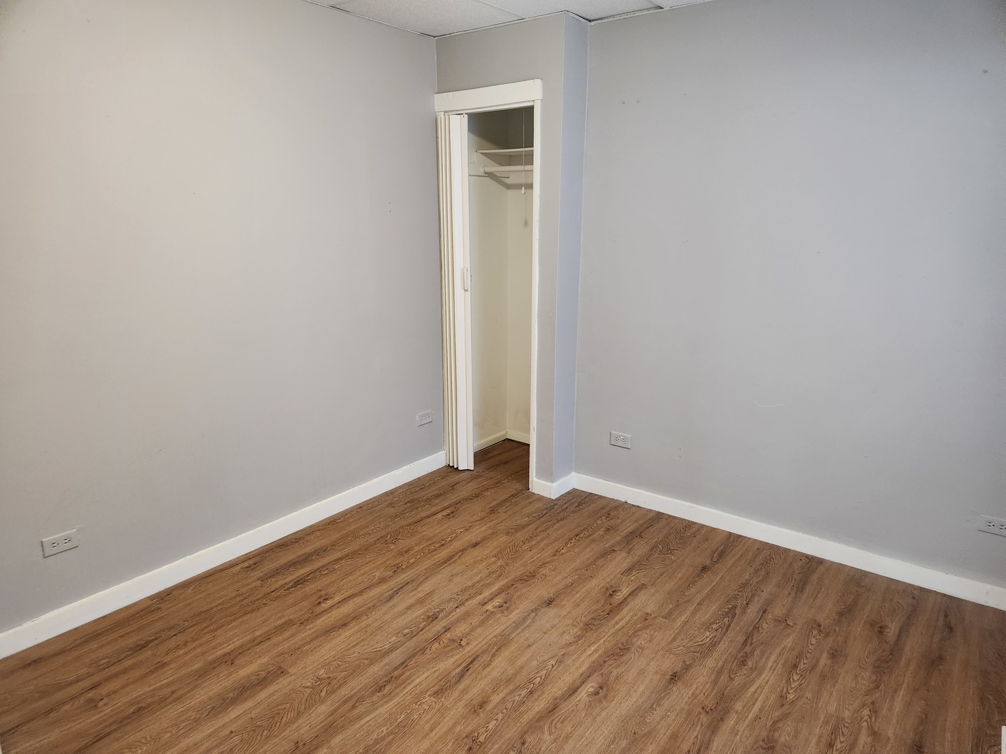 106 West Comanche Avenue, Unit 1E Shabbona, IL 60550 - Photo 5 of 9 a view of an empty room with wooden floor and a window