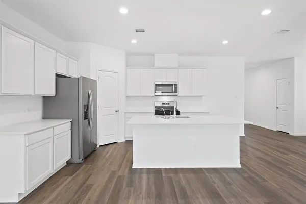 a large kitchen with stainless steel appliances a refrigerator and a stove top oven