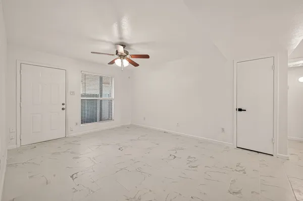 an empty room with chandelier fan and windows