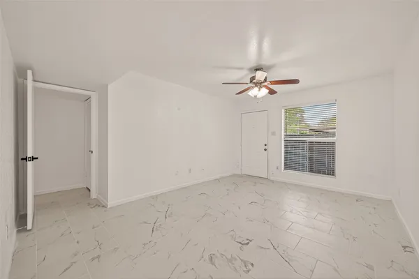 an empty room with a ceiling fan and a window
