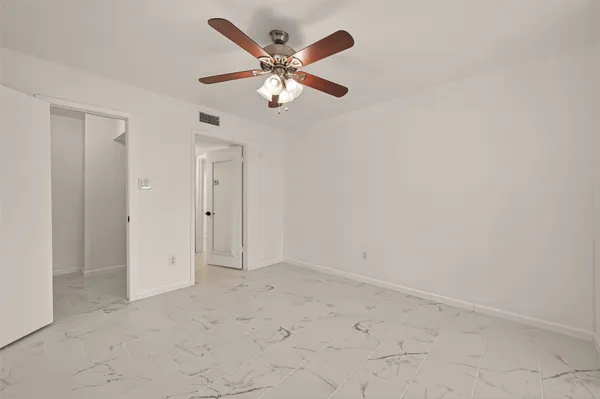 an empty room with closet and a chandelier fan
