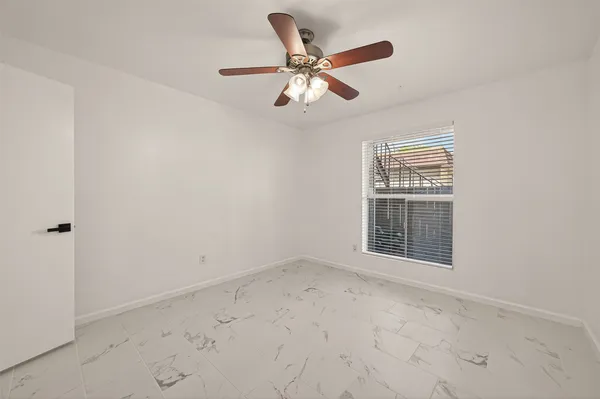 an empty room with windows and fan