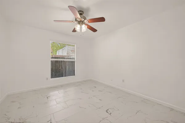 an empty room with windows and fan