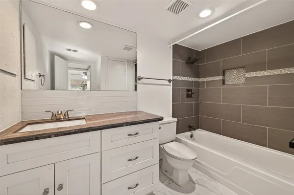 a bathroom with a granite countertop sink a toilet and bathtub