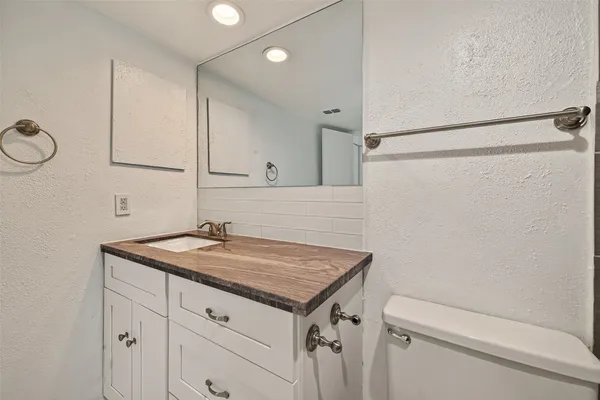 a bathroom with a granite countertop sink toilet and a mirror