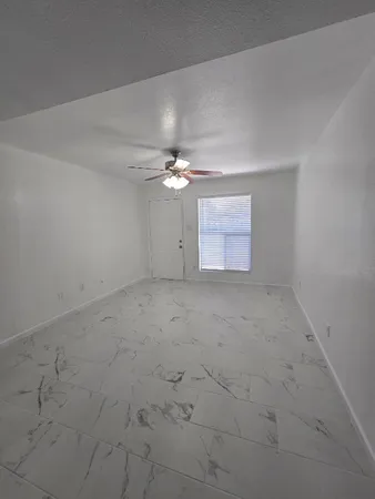 an empty room with a chandelier fan and windows