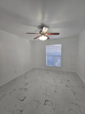an empty room with a ceiling fan and window