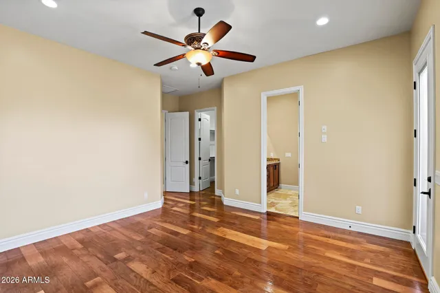 an empty room with wooden floor and ceiling fan