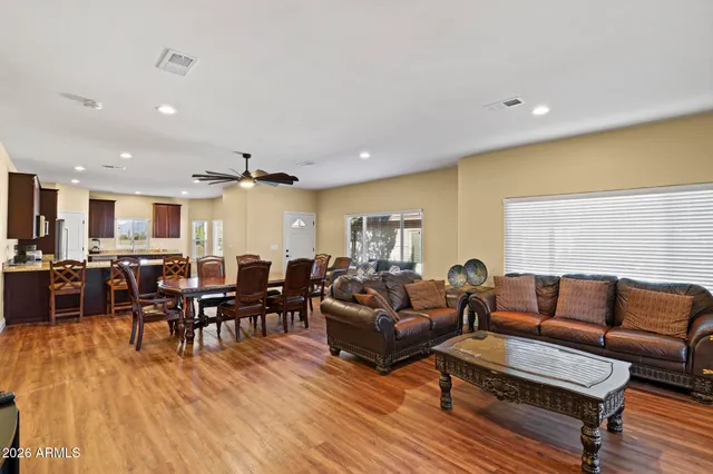 a living room with furniture a wooden floor and kitchen view