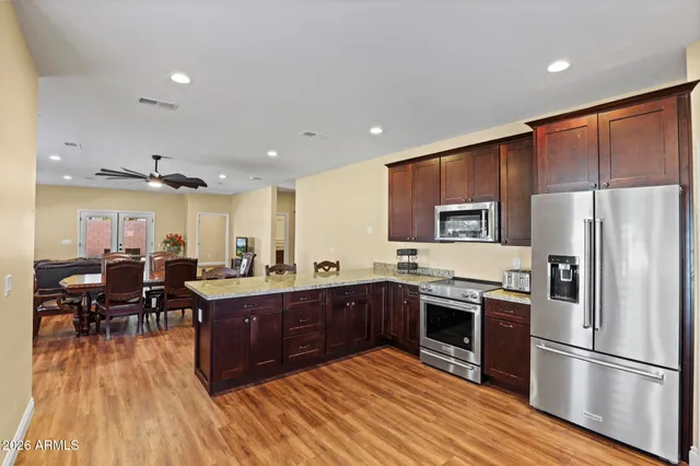 a kitchen with stainless steel appliances granite countertop a refrigerator a sink dishwasher a stove with wooden cabinets and floor