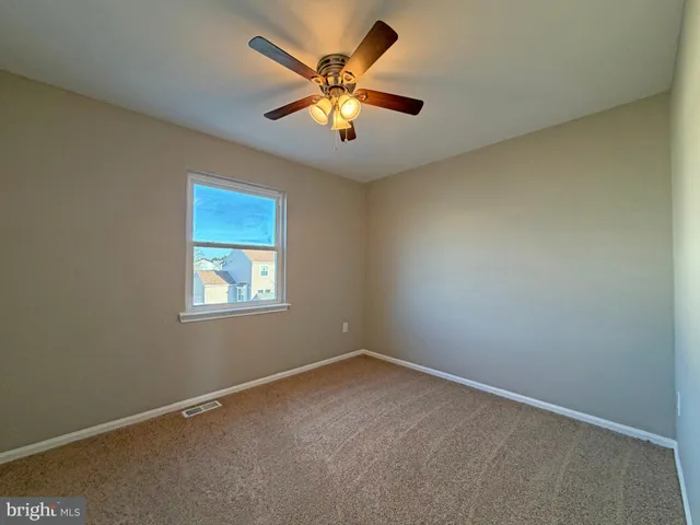 an empty room with ceiling fan and window