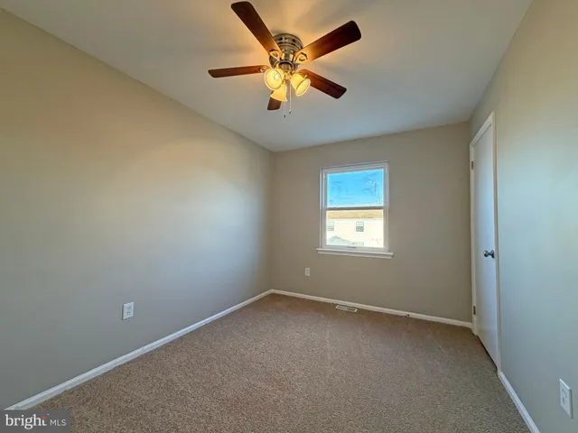 an empty room with ceiling fan and window