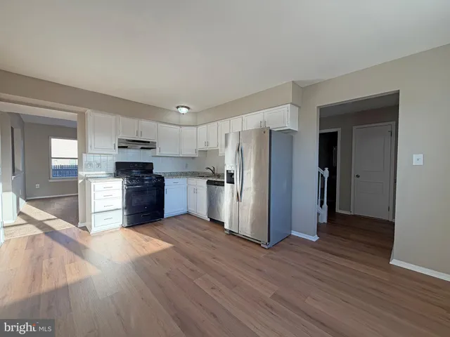 a kitchen with stainless steel appliances wooden floors and view living room