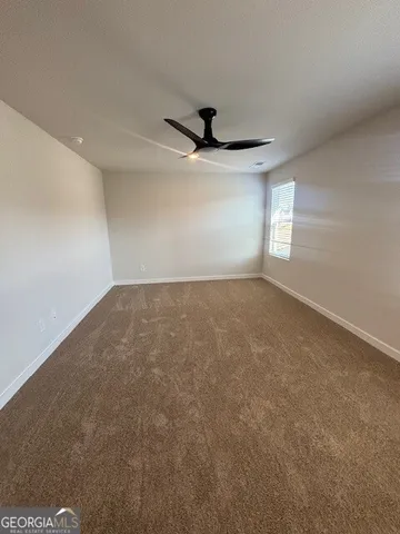 an empty room with windows and ceiling fan