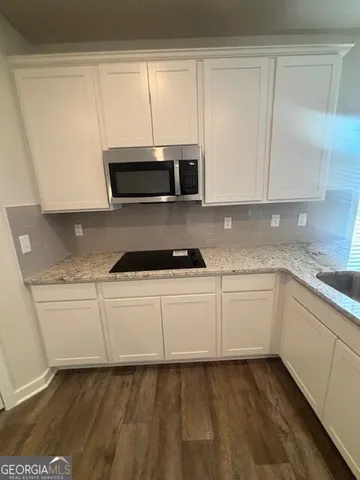 a kitchen with granite countertop white cabinets and stainless steel appliances
