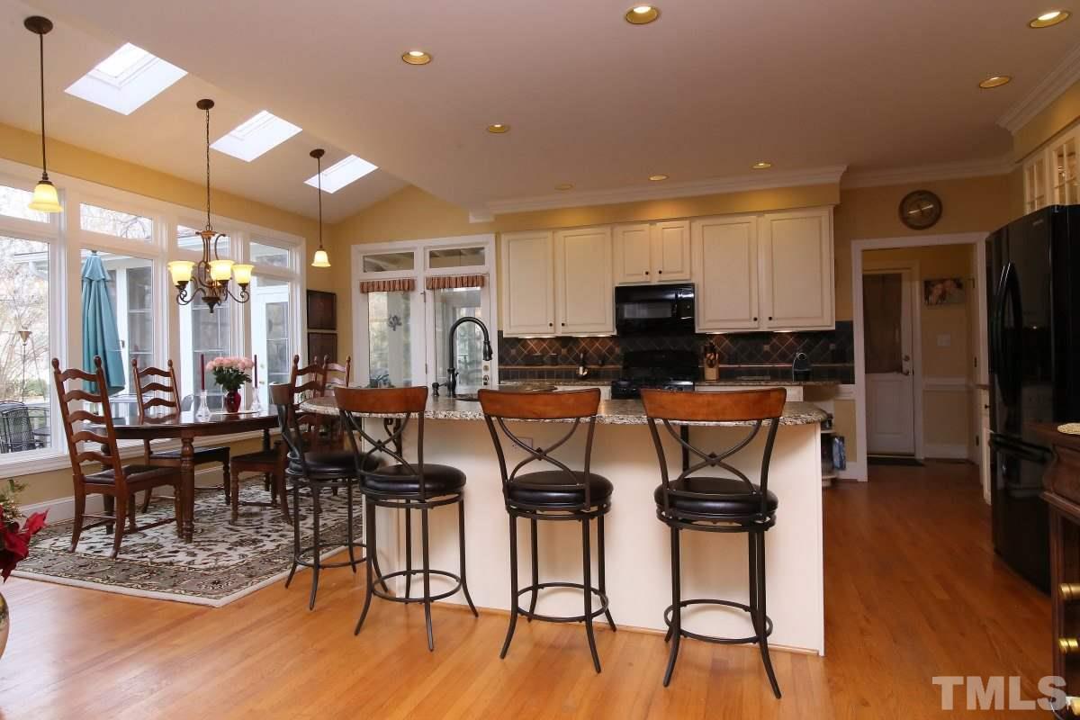 2908 Ballybunion Way Raleigh, NC 27613 - Photo 9 of 25 a kitchen with stainless steel appliances kitchen island granite countertop a table chairs and a refrigerator
