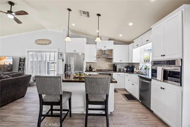 a kitchen with stainless steel appliances kitchen island granite countertop a table chairs and a refrigerator