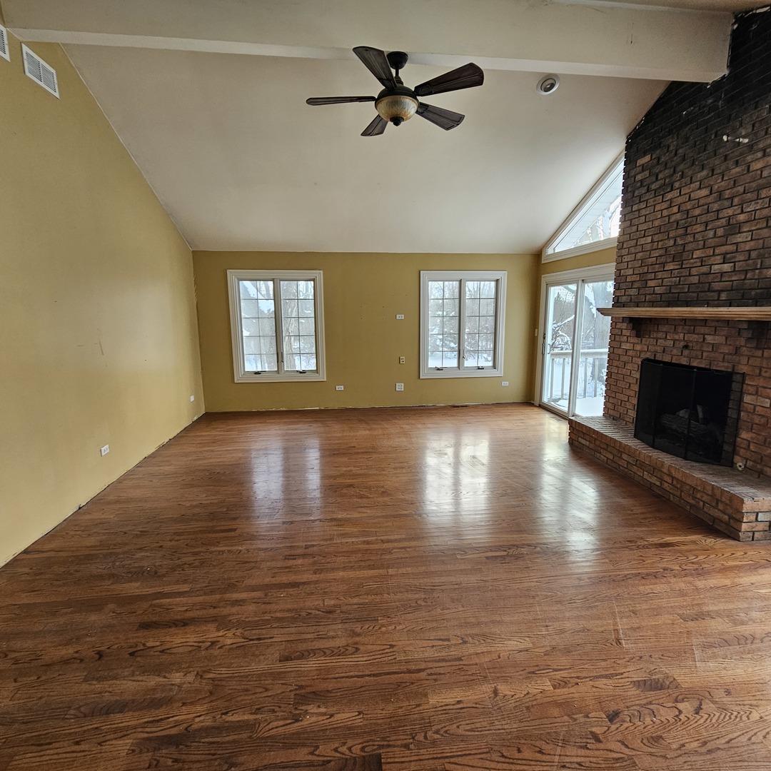 181 Old Sutton Road Barrington, IL 60010 - Photo 6 of 21 a view of a livingroom with wooden floor a fireplace and windows
