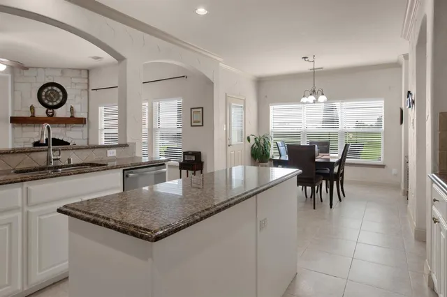 a kitchen with granite countertop a table chairs a sink dishwasher a dining table and cabinets