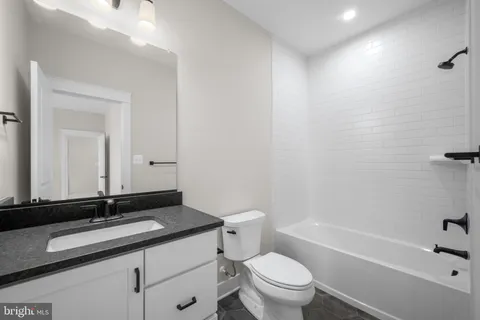 a bathroom with a granite countertop sink a toilet and a bathtub