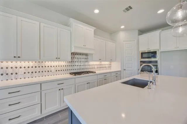 a kitchen with granite countertop a sink a stove a refrigerator and white cabinets