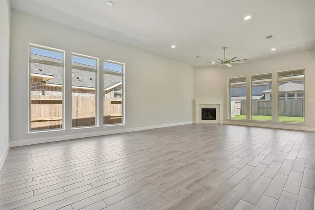 a view of an empty room with window and wooden floor
