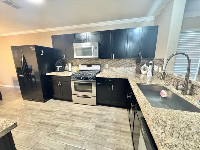 a kitchen with stainless steel appliances granite countertop a sink stove and refrigerator