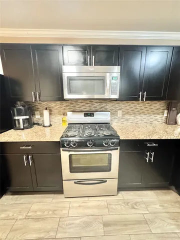 a kitchen with stainless steel appliances granite countertop a stove a sink and a microwave