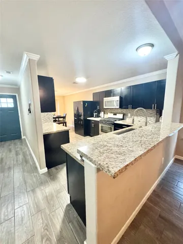 a kitchen with kitchen island granite countertop a sink stove and refrigerator
