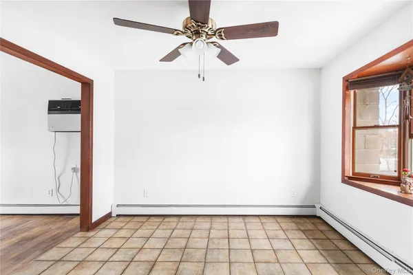 a view of an empty room with window and chandelier fan