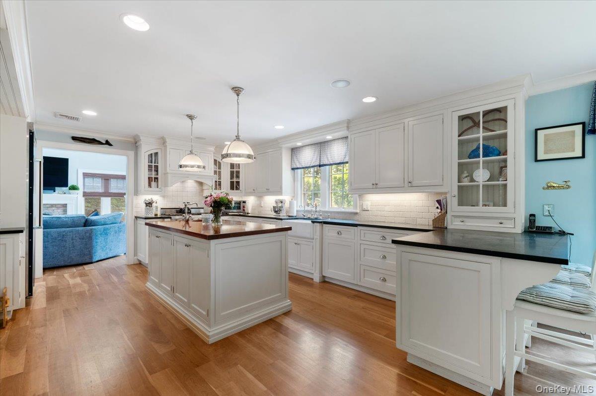 5 Fox Hunt Court Cold Spring Harbor, NY 11724 - Photo 13 of 42 Spacious kitchen featuring light wood-finish flooring, white cabinetry with glass-front accents, and a large central island with a wood-finish countertop