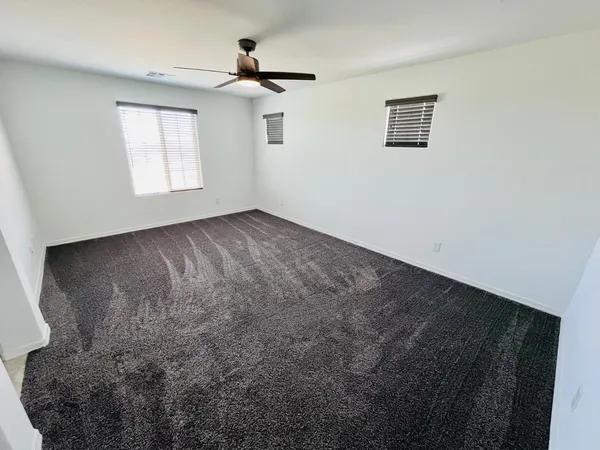 a view of a big room with windows and chandelier fan