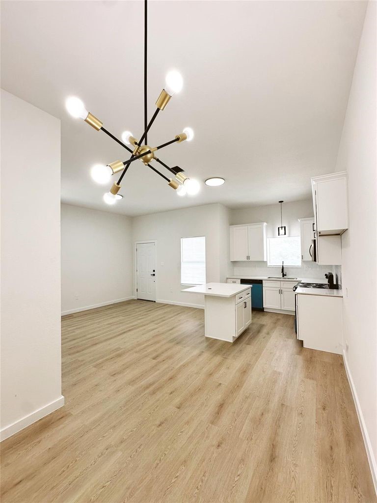 9705 Garcroft Street, Unit A Houston, TX 77029 - Photo 20 of 21 a view of a kitchen with kitchen island a stove a sink dishwasher and a dining table with wooden floor