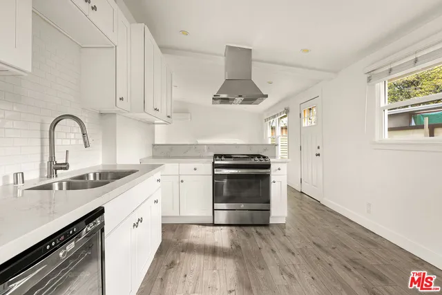 a kitchen with granite countertop a sink cabinets stainless steel appliances and a window