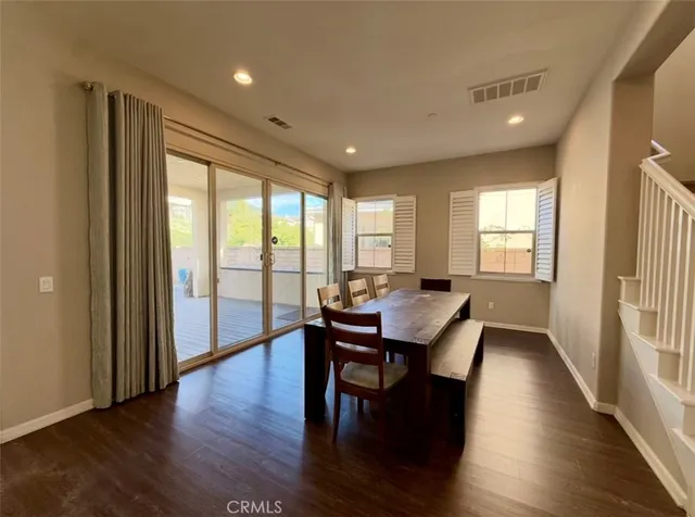 a open kitchen with stainless steel appliances kitchen island granite countertop a stove a refrigerator a dining table and chairs with wooden floor