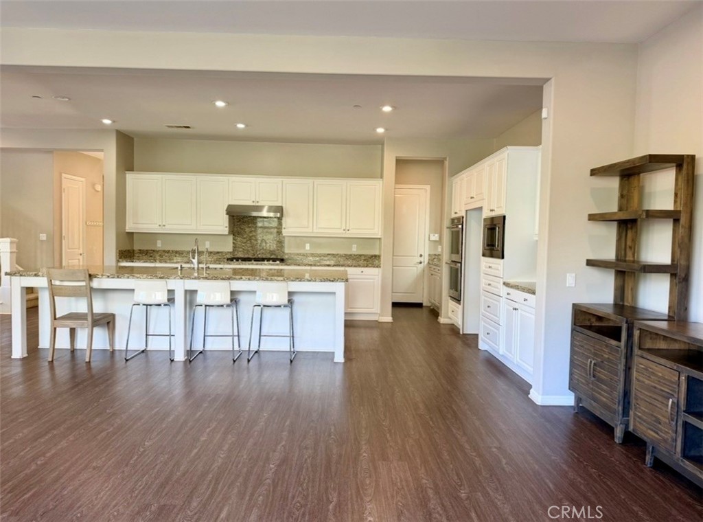 667 Desert Willow Road Azusa, CA 91702 - Photo 36 of 75 a open kitchen with stainless steel appliances kitchen island granite countertop a stove a refrigerator a dining table and chairs with wooden floor