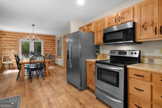 a kitchen with stainless steel appliances granite countertop a stove a microwave a refrigerator a dining table and chairs with wooden floor