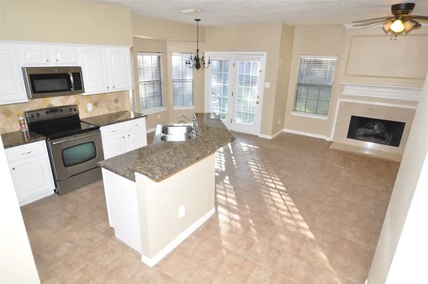 a kitchen with granite countertop a stove top oven a sink dishwasher a dining table and a fireplace with wooden floor