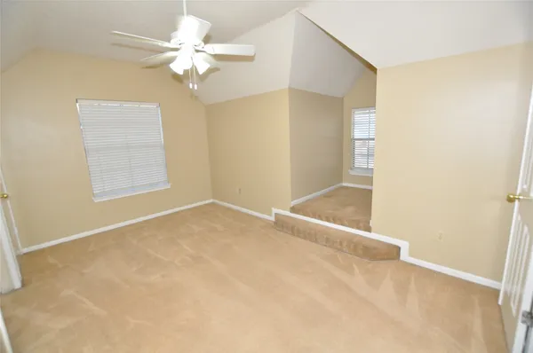 an empty room with windows and fan