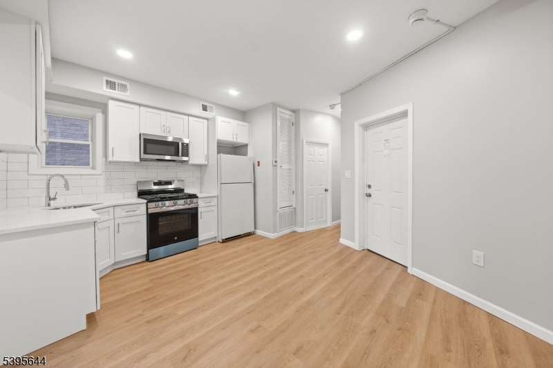 57 Henry Street, Unit A1 Passaic, NJ 07055 - Photo 2 of 14 a kitchen with kitchen island a sink stainless steel appliances and cabinets