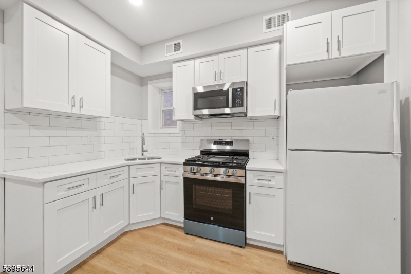 57 Henry Street, Unit A1 Passaic, NJ 07055 - Photo 4 of 14 a kitchen with white cabinets and stainless steel appliances