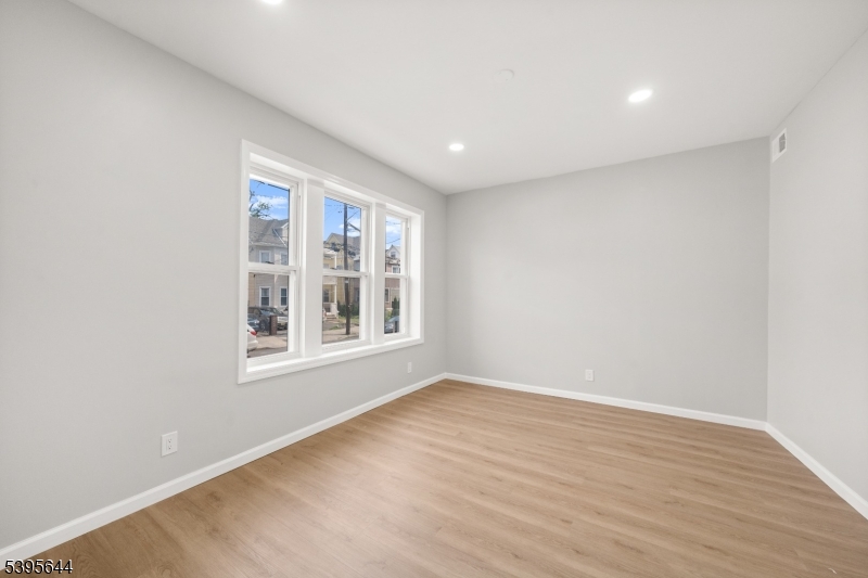 57 Henry Street, Unit A1 Passaic, NJ 07055 - Photo 7 of 14 an empty room with wooden floor and windows