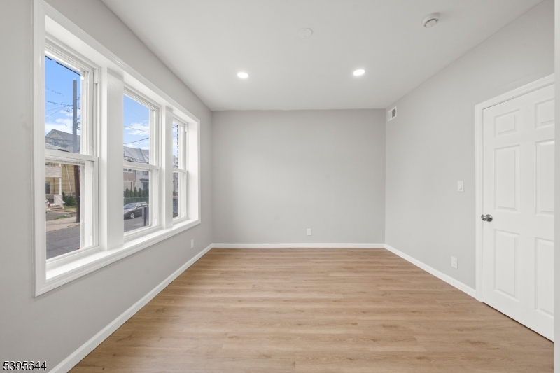 57 Henry Street, Unit A1 Passaic, NJ 07055 - Photo 8 of 14 a view of an empty room with wooden floor and a window